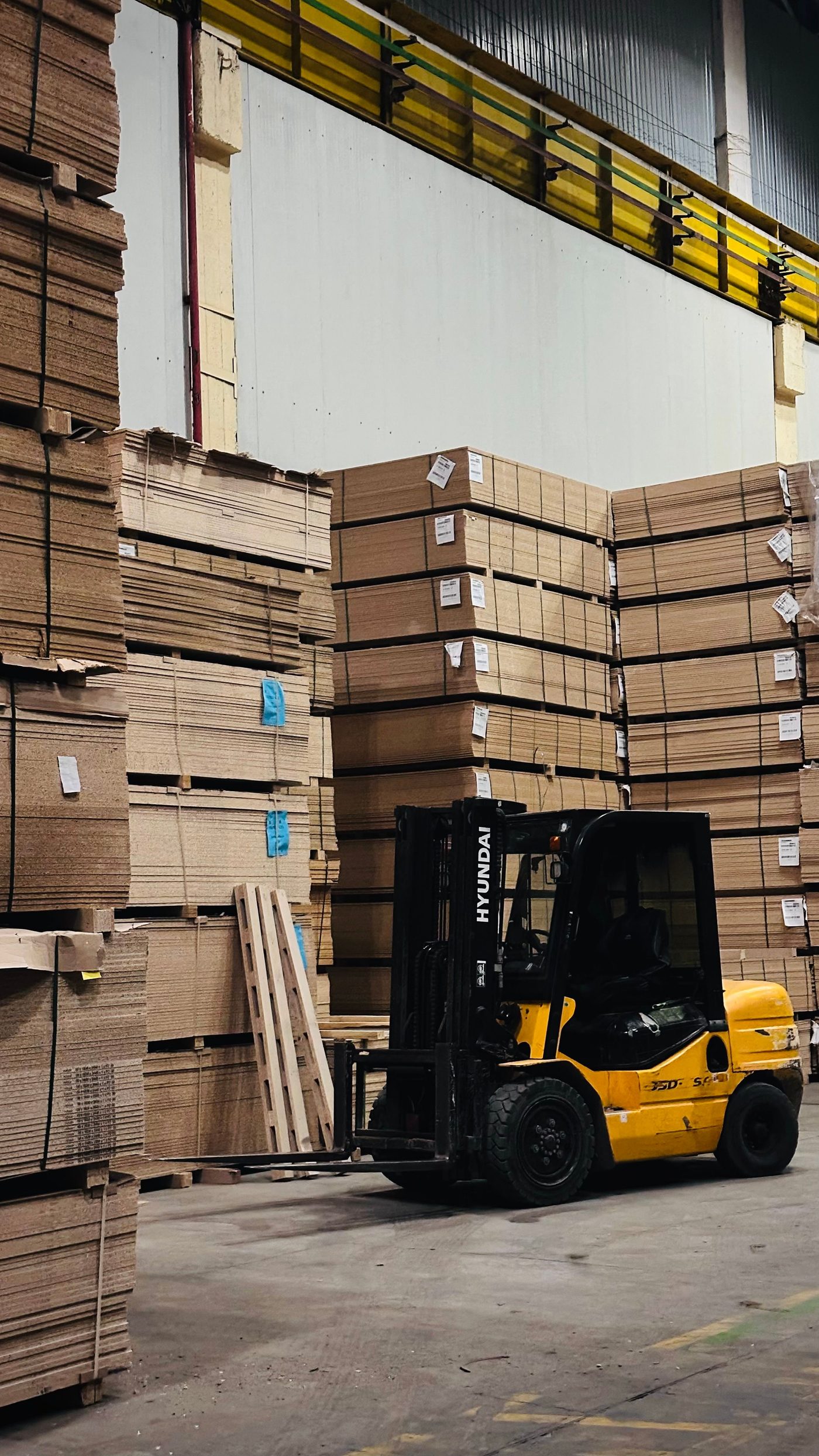 Forklift moving stacked panel stock in a warehouse